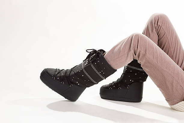 woman's legs in beige pants and moon boots. warm ski boots.